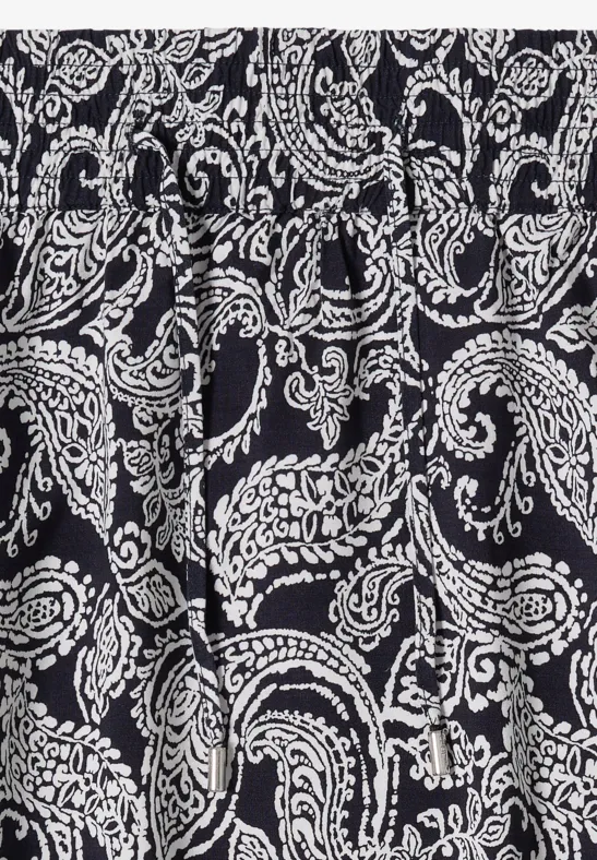 Schwarzer Stoff mit weißem Paisley-Muster, geschwungene Ornamente und Blüten.