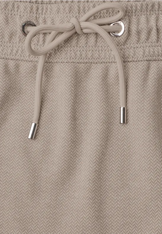 Beige herringbone-stof met trekkoord en metalen uiteinden in de taille van een kledingstuk