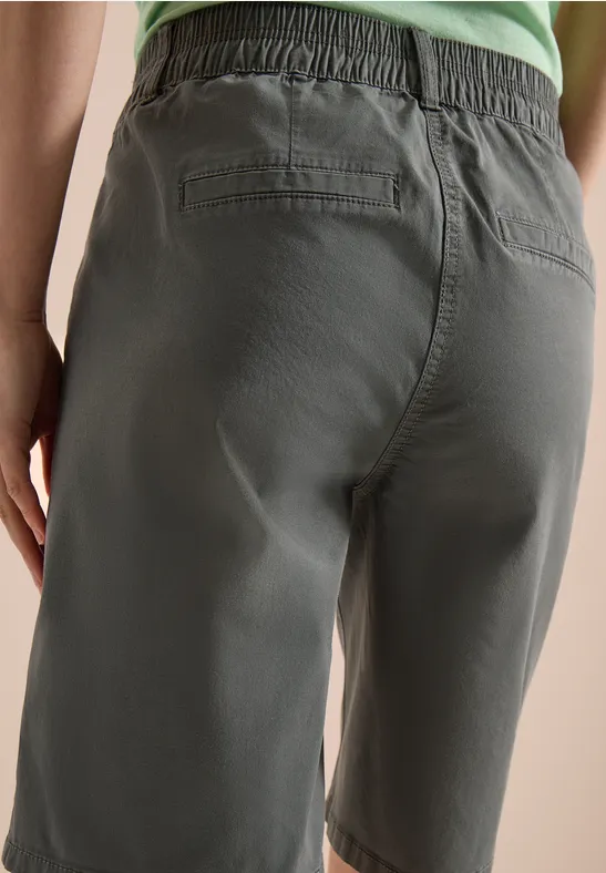 Achteraanzicht van een persoon in olijfgroene bermudashorts en groen topje.