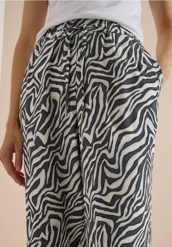 Une personne porte un pantalon zèbre noir et blanc avec cordon de serrage et poches.