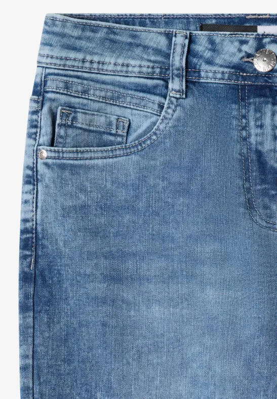 Close-up van blauwe spijkerbroek met voorzak, muntvak, riemlussen en zichtbare stiksels.