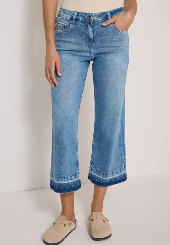 Lichtblauwe, wijdvallende cropped jeans met omslag en beige loafers.