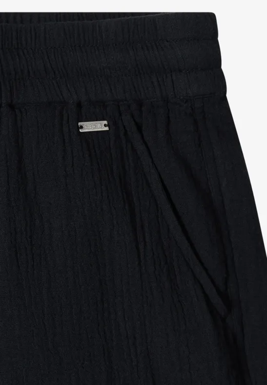 Textilhose aus schwarzem, geripptem Stoff mit elastischem Bund und Seitentaschen.