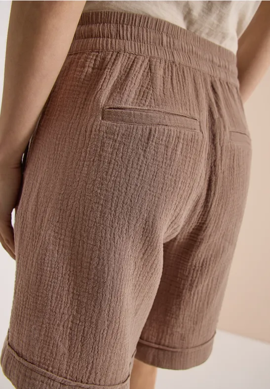 Beige lockere Baumwoll-Shorts mit elastischem Bund und Gesäßtasche, von hinten aufgenommen.