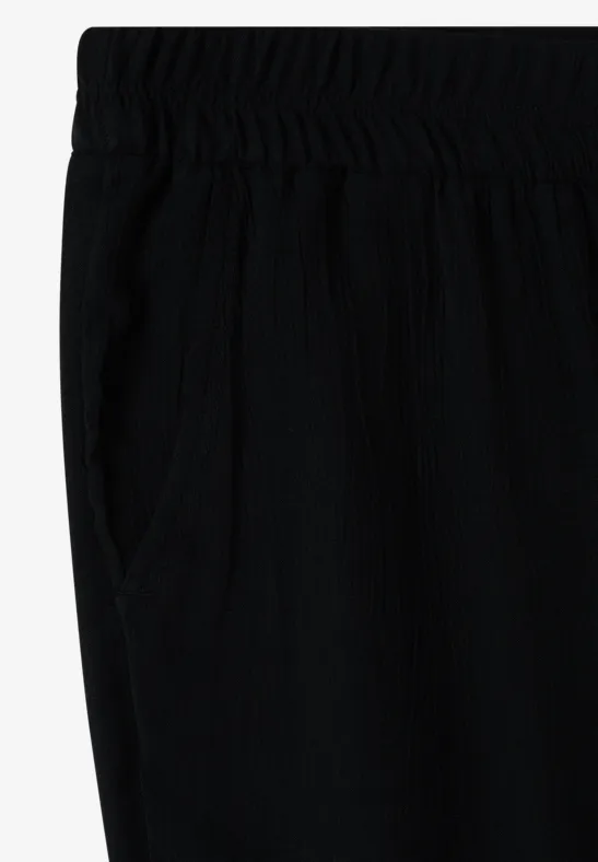 Zwarte, losse broek met elastische taille en zijzak.