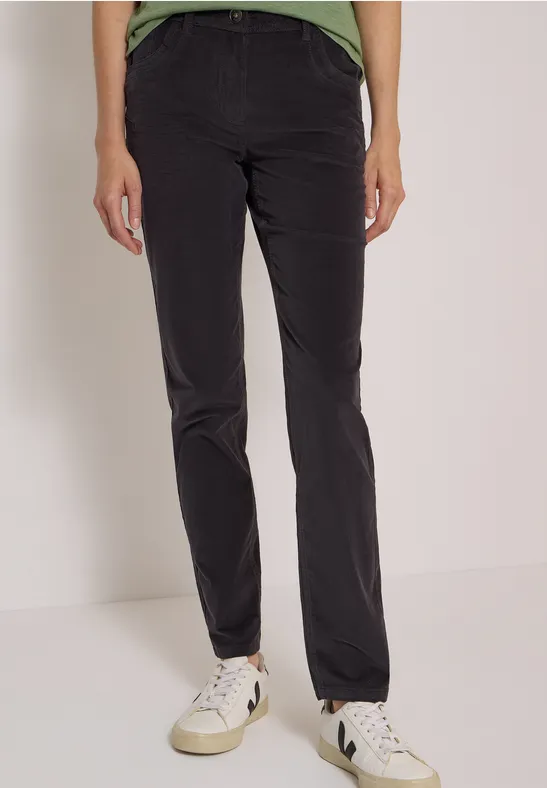 Pantalon noir et baskets blanches portés par un mannequin, photo prise sur fond clair.
