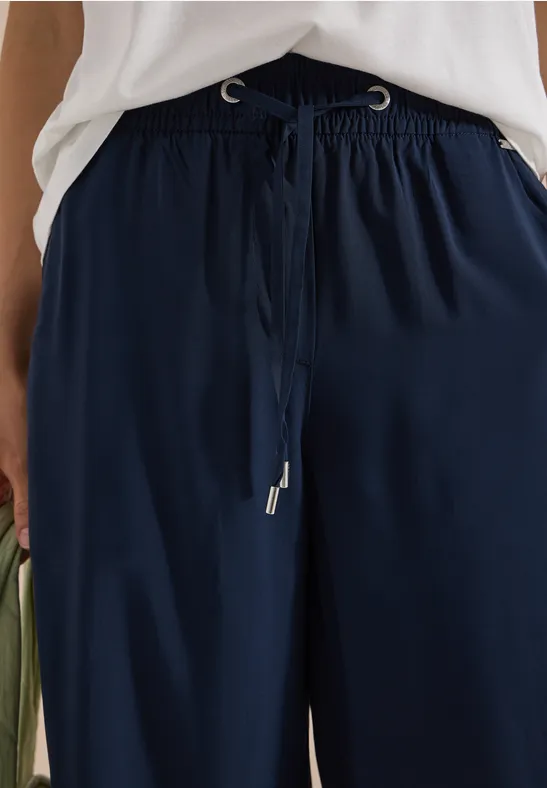 Dunkelblaue, weite Hose mit Kordelzugbund in der Taille, vorne gebunden.