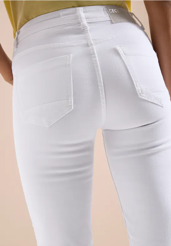 Eng anliegende weiße Jeans an Person, Rückenansicht vor neutralem Hintergrund.