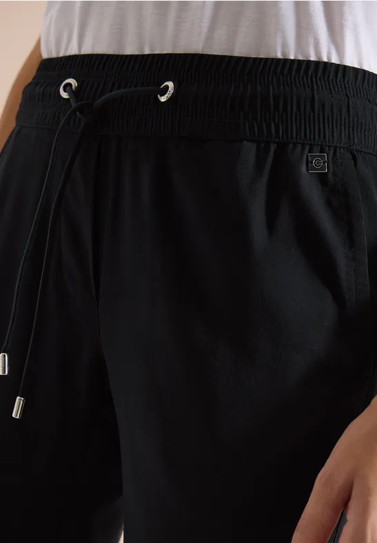 Close-up van een zwarte broek met elastische taille en koordsluiting.