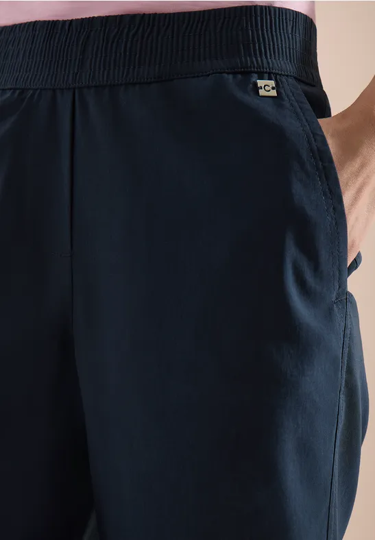 Donkerblauwe, luchtige joggingbroek met elastische taille, zijzak en klein merkembleem.