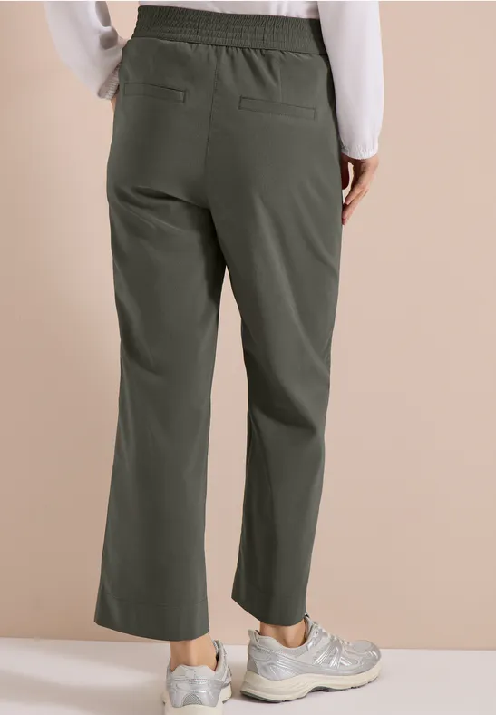 Damesbroek in kaki met elastische taille, rechte, losse pasvorm, gecombineerd met sneakers.