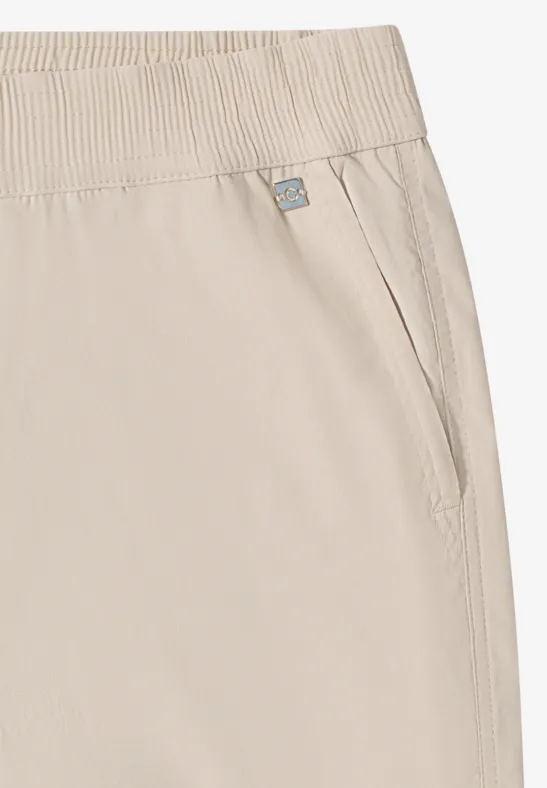 Lichtbeige broek met elastische taille, zijzak en klein label.
