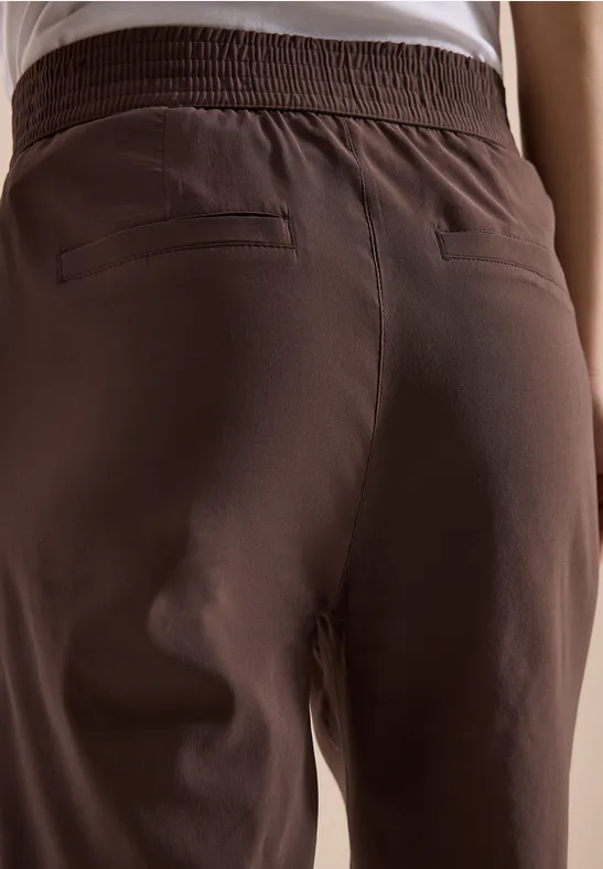 Achteraanzicht van een persoon met een bruine broek en wit shirt.