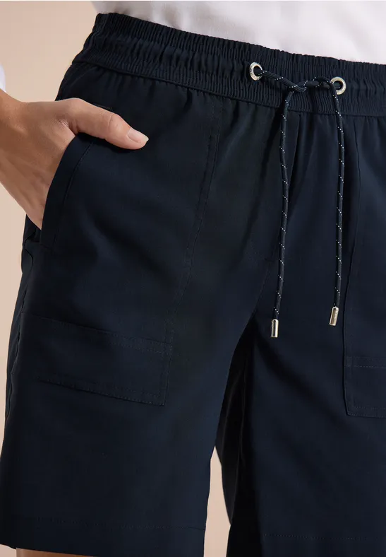 Donkerblauwe, casual broek met trekkoord en opgestikte zakken, hand in de zak.