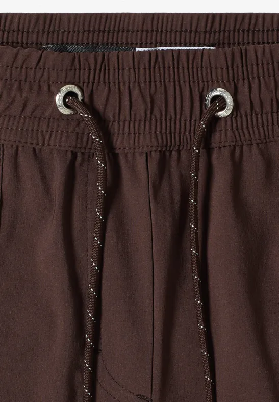 Close-up van een bruine broek met elastische tailleband en trekkoorden.