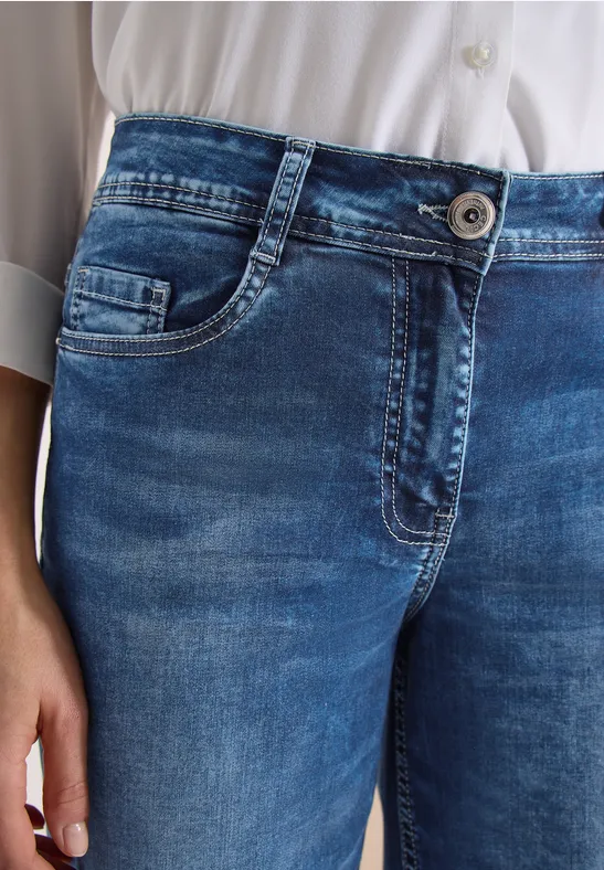 Nahaufnahme einer Person in blauen Jeans und weißem Hemd.