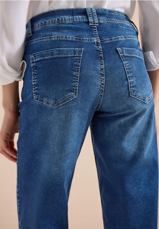 Eine Person von hinten in blauen Jeans und weißem Hemd.