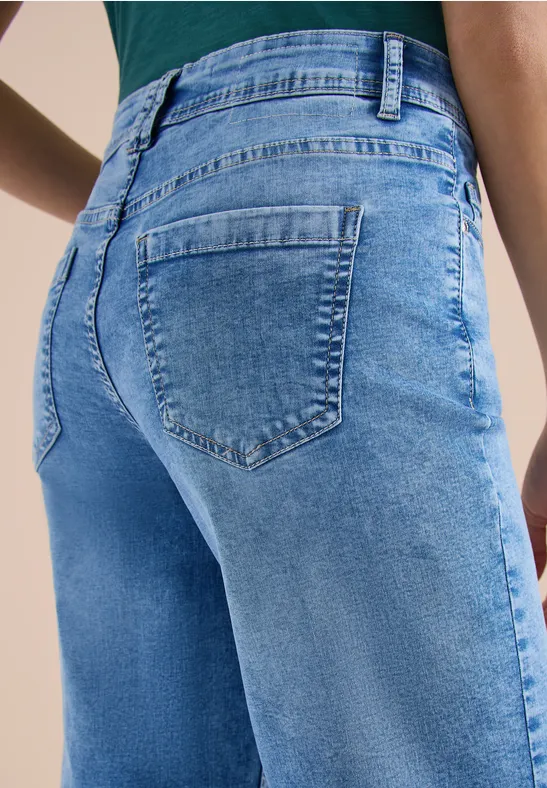 Een persoon draagt een strakke blauwe jeans, close-up van de achterkant en zakken.