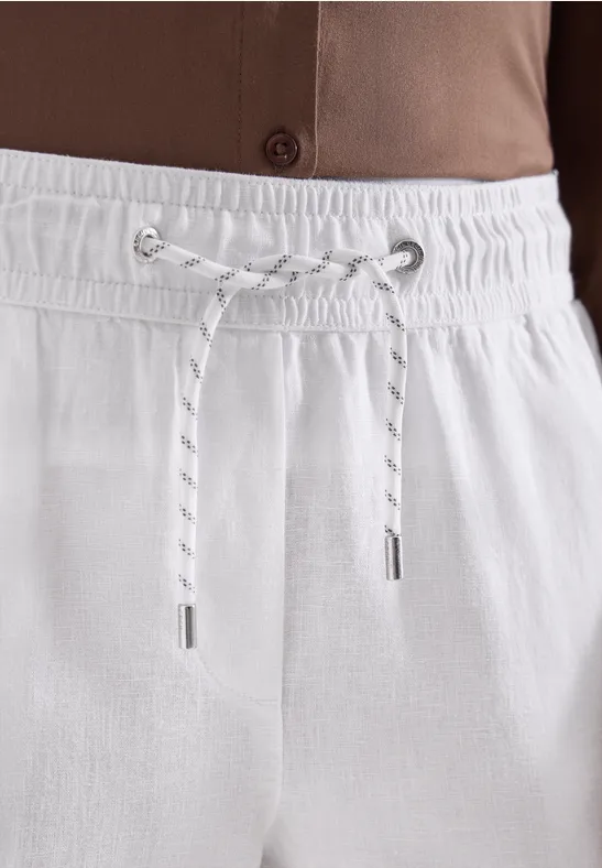 Makroaufnahme von weißen Leinenhosen mit elastischem Bund und Kordel.