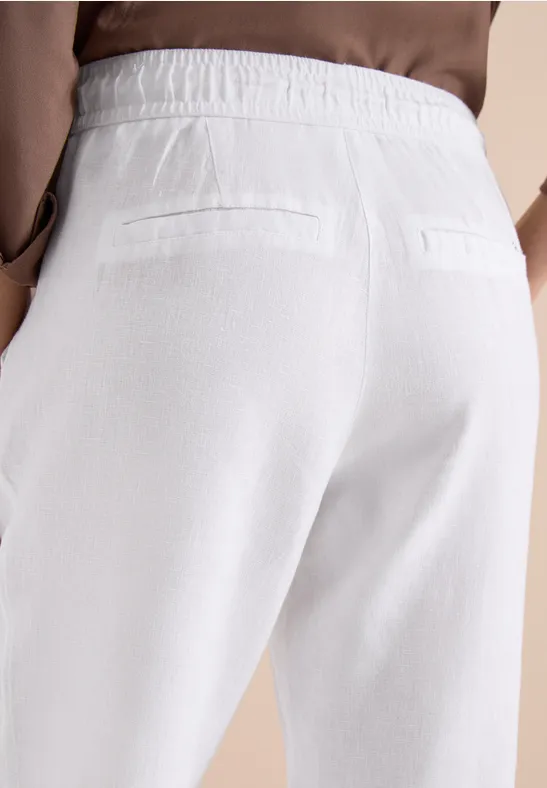 Rückansicht einer Person in weißen Stoffhosen mit elastischem Bund und zwei Gesäßtaschen.