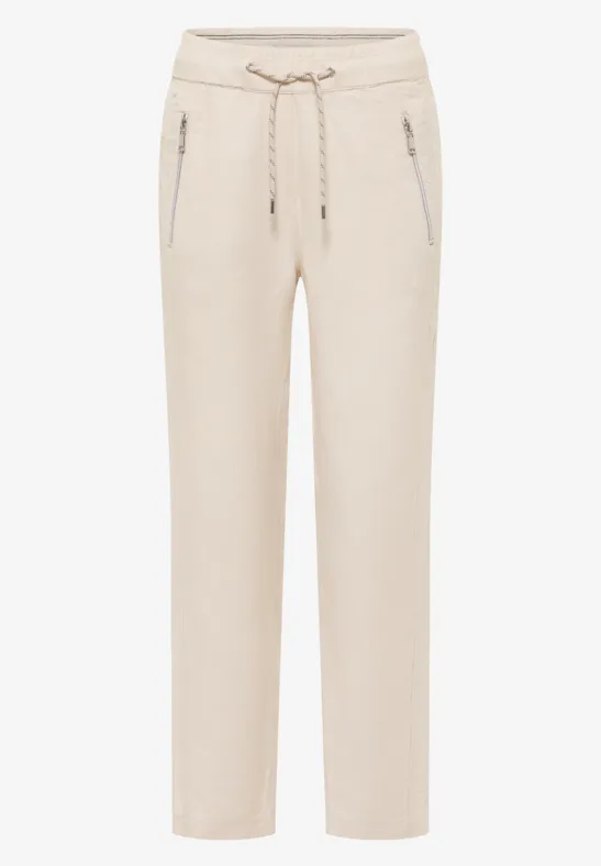 Helle, beige-farbene Hose mit elastischem Bund, Kordelzug und seitlichen Reißverschlusstaschen.