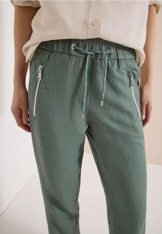 Modische hellgrüne Freizeithose mit elastischem Bund, Kordelzug und seitlichen Reißverschlusstaschen.