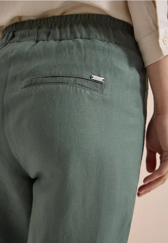 Grüne Leinenhose mit elastischem Bund und Reißverschlusstasche hinten, lässiger Sitz.