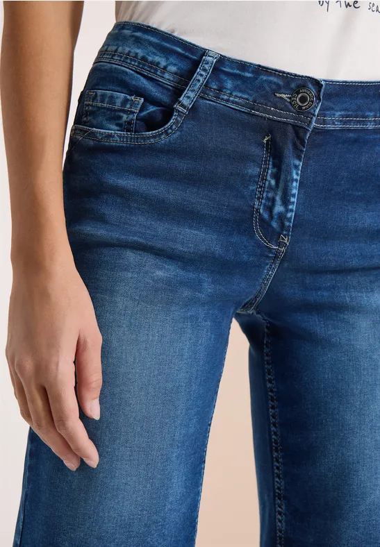 Eine Person trägt blaue Jeans, sichtbar von Hüfte bis Oberschenkel, Hand entspannt an der Seite.