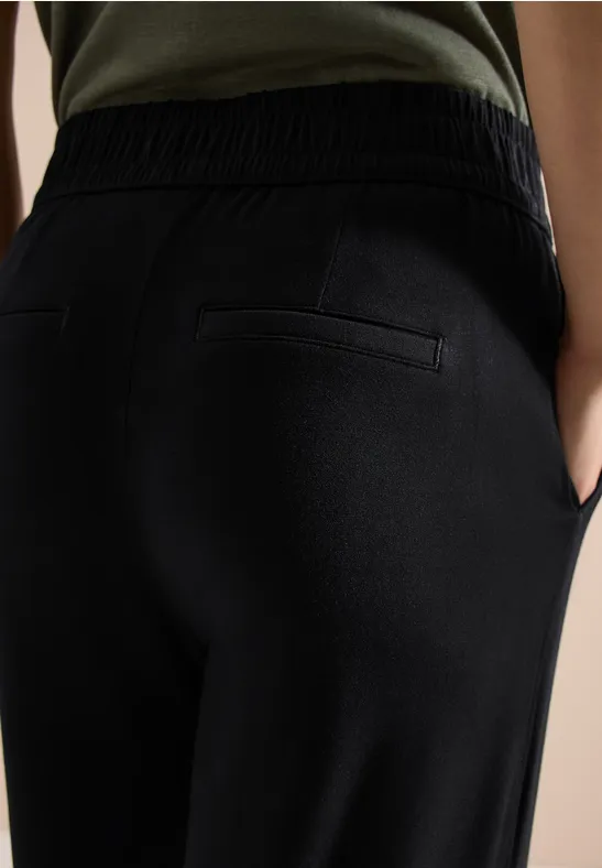 Ansicht eines Rückenteils in schwarzen Jogginghosen mit Gummibund und Gesäßtasche.