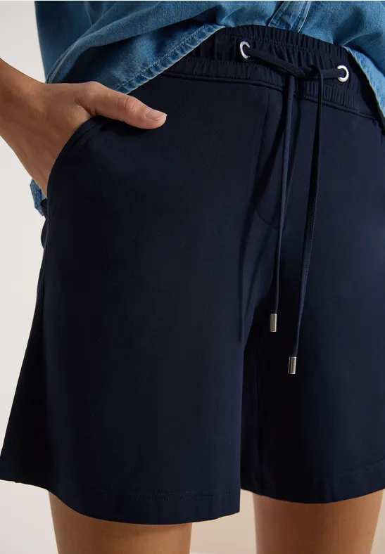 Dunkelblaue Shorts mit Kordelzug und seitlichen Taschen, getragen mit passendem dunkelblauen Oberteil.