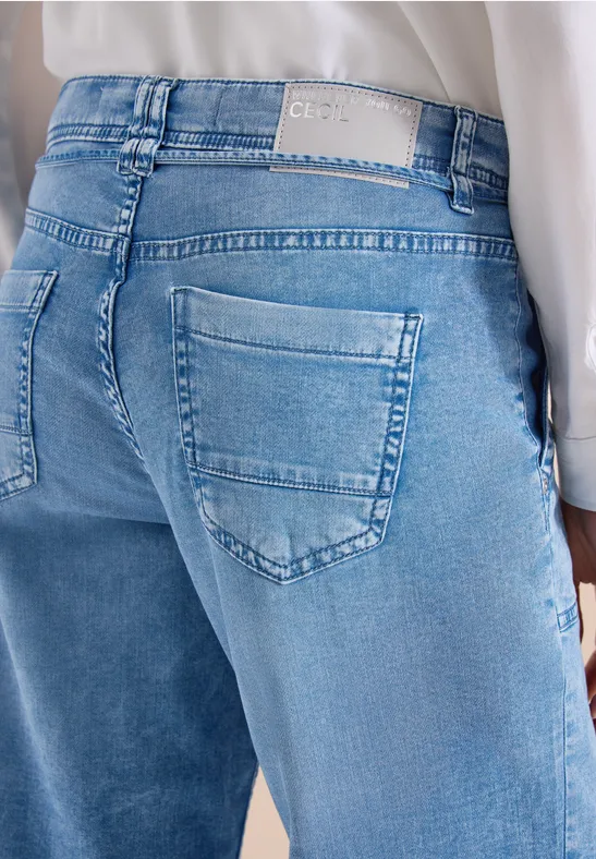 Rückansicht einer Person in hellblauen Jeans und weißem Oberteil.