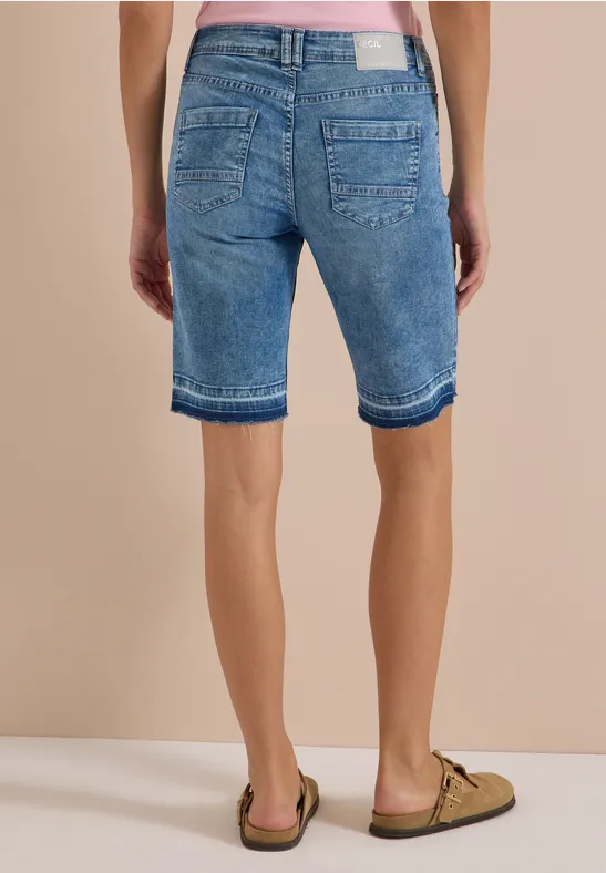 Vue arrière d'une personne portant des bermudas en jean et des sandales.