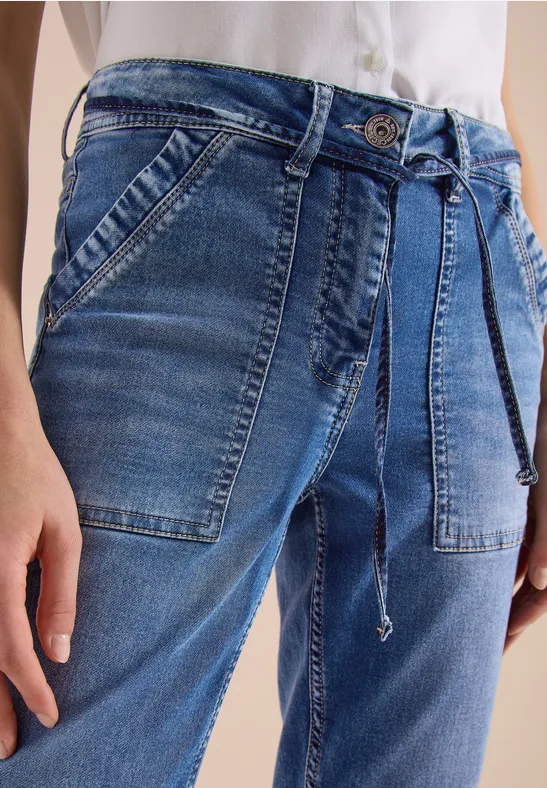 Blaue Jeans mit aufgesetzten Taschen und Kordelgürtel, weiße Bluse