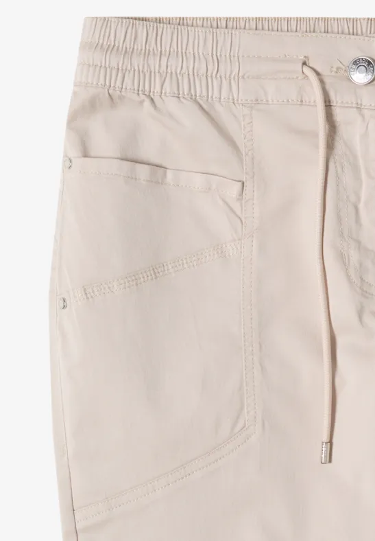 Beige Baumwollhose mit elastischem Bund, Kordelzug und seitlicher Tasche.