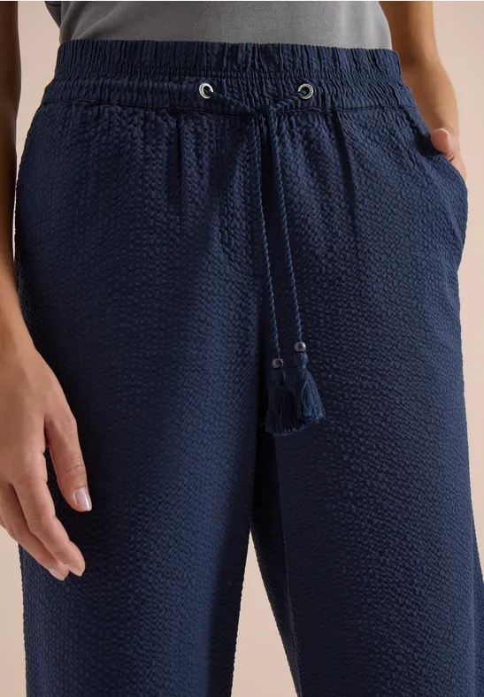 Donkerblauwe, gestructureerde broek met elastische taille en kwastjeskoord.