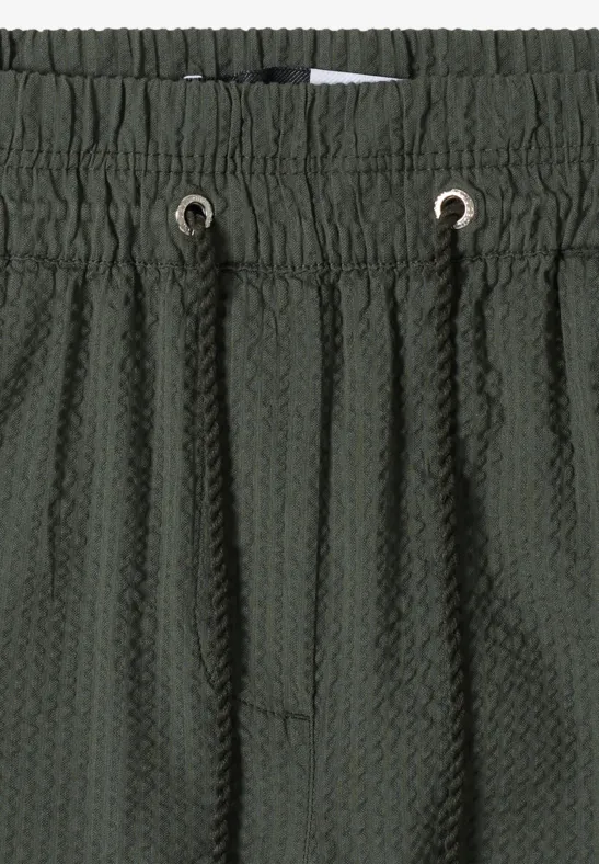 Donkergroene, gestructureerde short met elastische taille, aantrekkoord en honingraatstructuur.