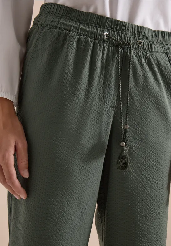 Donkergroene, gestructureerde losse broek met elastische taille en koordsluiting met kwastjes.