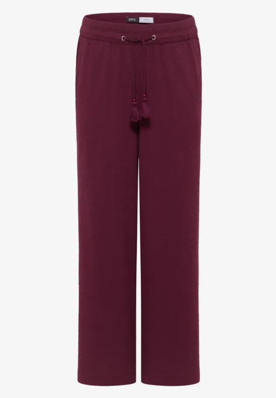 Bordeauxrote, weit geschnittene Damenhose mit Kordelzug und Quasten.