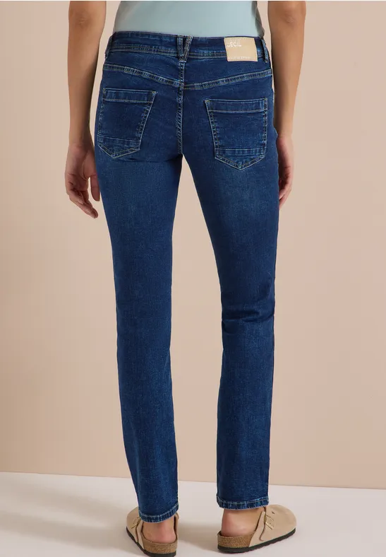 Femme vue de dos portant un jean bleu foncé droit et des sandales plates.