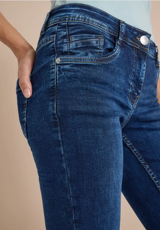 Vue latérale d'une personne en jean bleu foncé, main dans la poche.