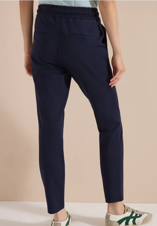 Dunkelblaue, schmale Jogginghose mit Gummizug und Taschen, Modell von hinten.