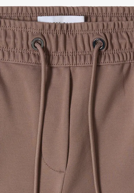 Nahaufnahme einer braunen Hose mit elastischem Bund und Kordelzug.