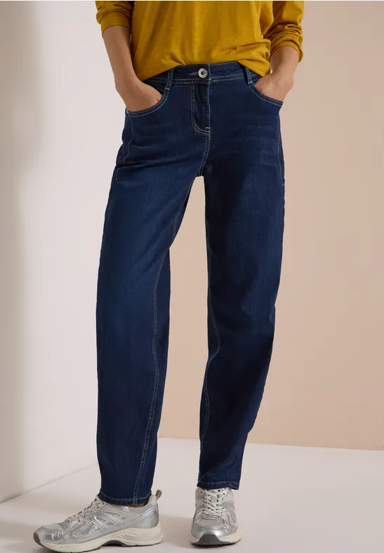 Dunkelblaue Jeans mit geradem Schnitt, aufgesetzten Taschen und silbernen Sneakern.
