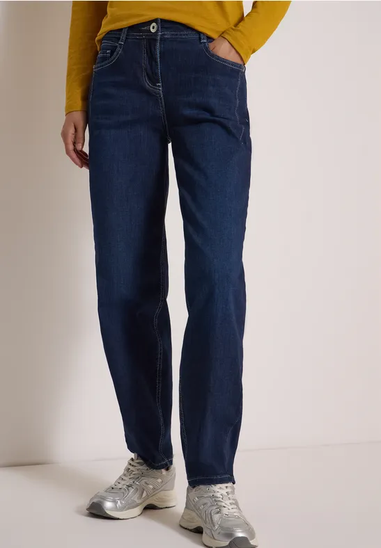 Dunkle Jeans im geraden Schnitt, getragen mit bequemen Sportschuhen.