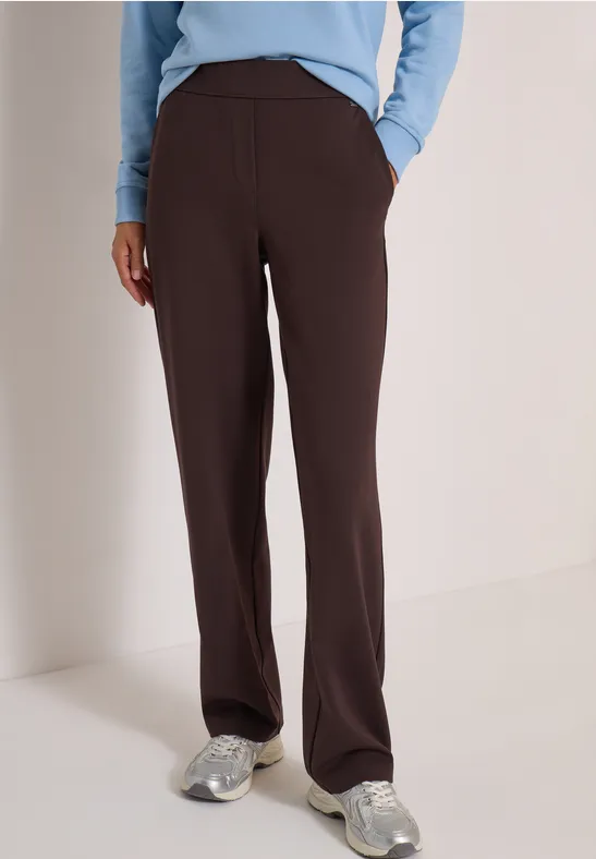 Pantalon droit marron foncé avec poches latérales, porté avec des baskets décontractées.