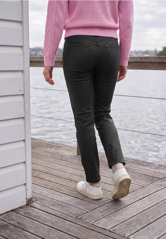 Person in rosa Pullover und schwarzen Hosen läuft auf einem Steg am Wasser.