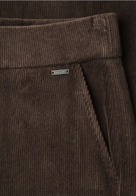 Nahaufnahme einer braunen Cordhose mit seitlicher Tasche und kleinem Metalletikett.