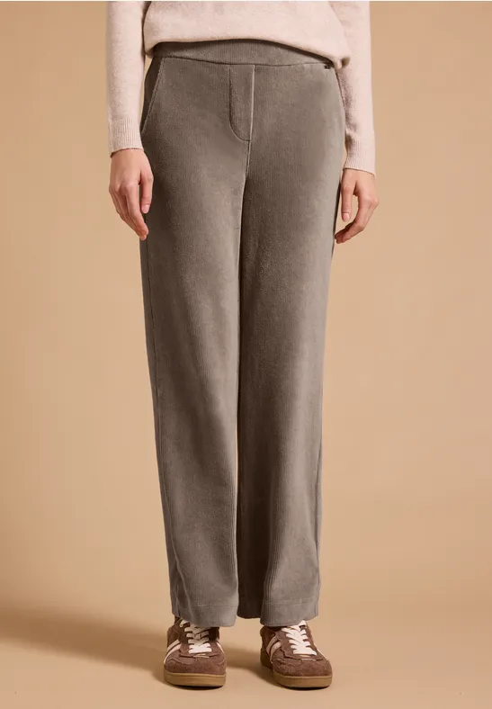 Pantalon de détente gris-brun droit, taille élastiquée, poches latérales, porté avec sneakers assorties.