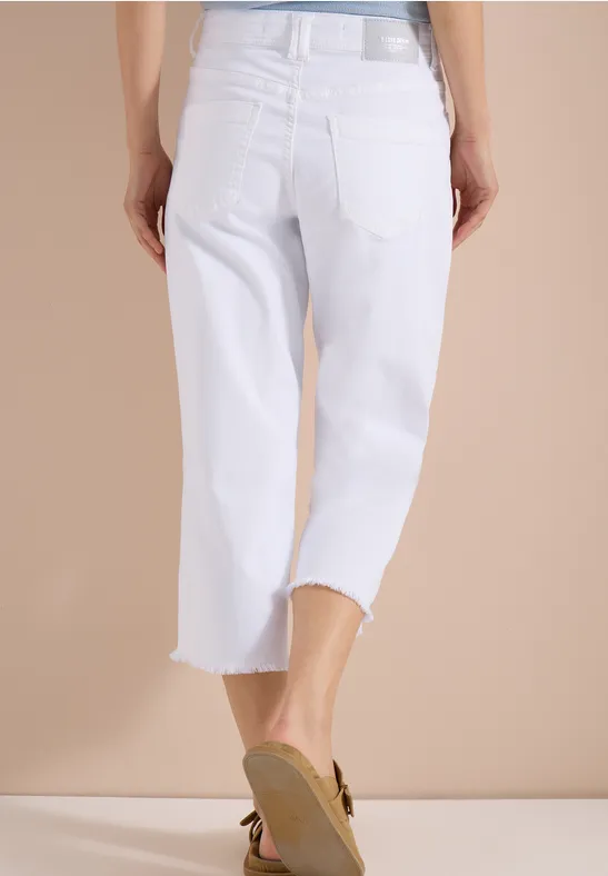 Rückansicht: weisse, knöchellange Jeans mit weitem Bein und beigen Sandaletten.