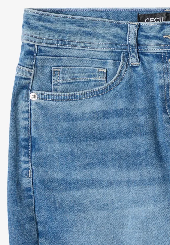 Gros plan d'un jean bleu clair avec poche, passants de ceinture et petite étiquette de marque
